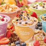 Variety of yogurt containers with fresh fruits and toppings.